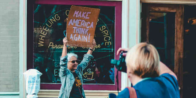 Woman holding sign - make America think again